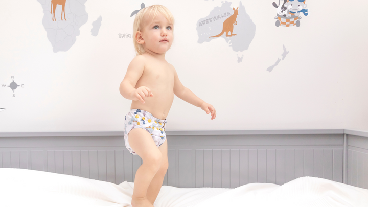 a boy is wearing cloth diaper and jumping on the bad