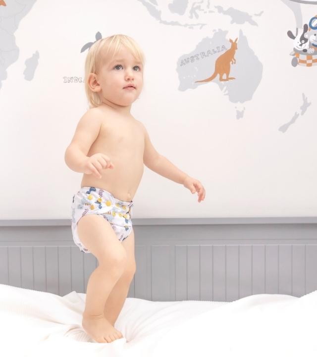 a boy is wearing cloth diapers and jumping on the bed