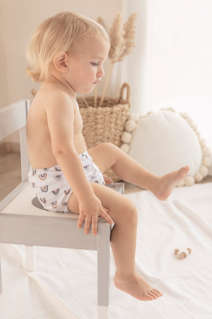 a baby boy is sitting in a chair, wearing baby elsa diapers