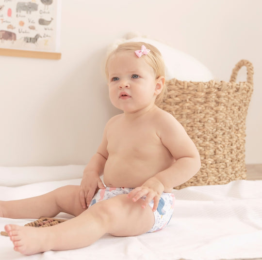 a girl sitting on the floor wearing cloth diaper